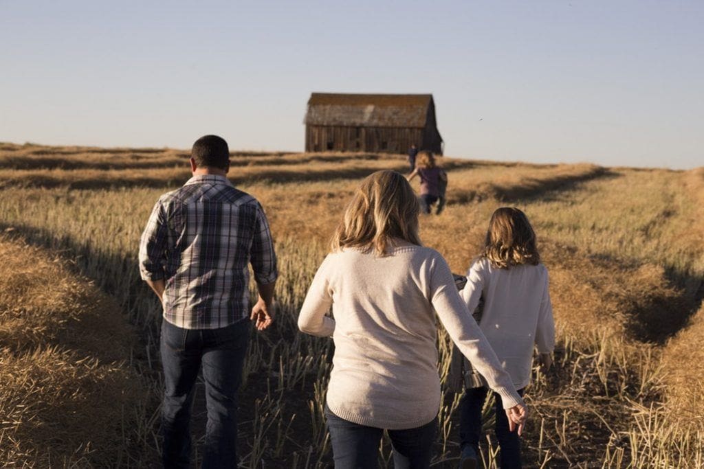 Family walking through field to old house