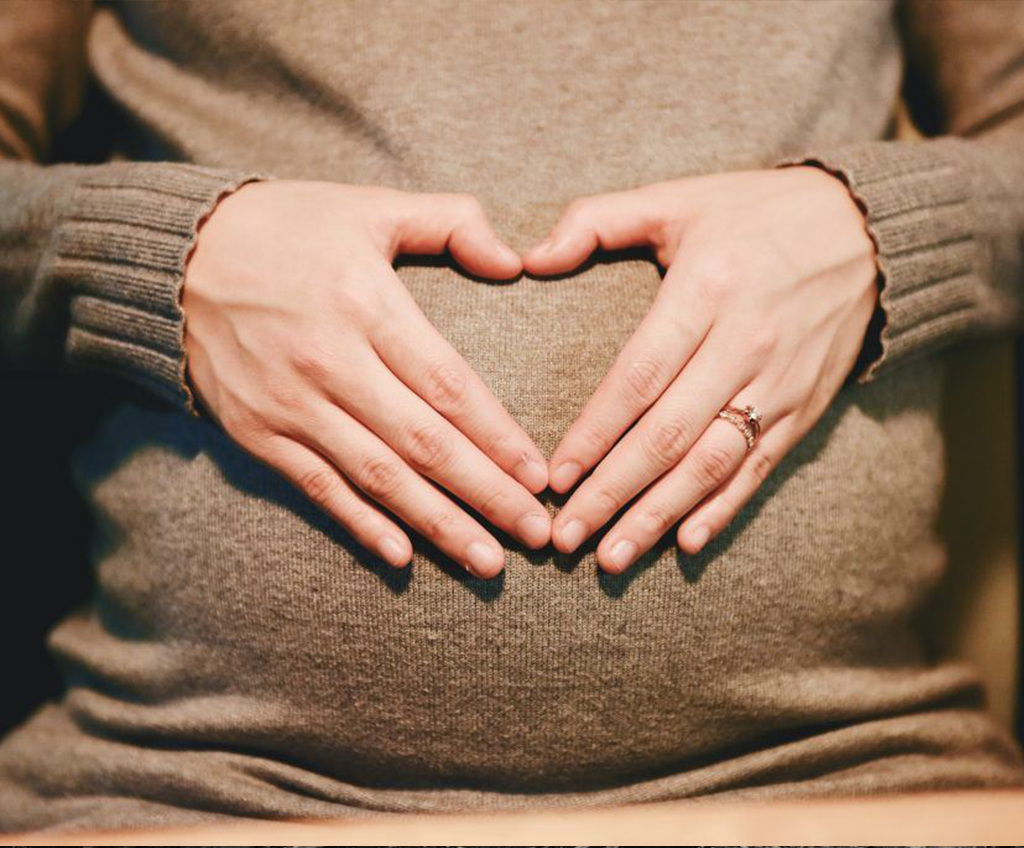 A Pregnant Woman Holding Her Hands in a Heart Shape on Her Baby Bump