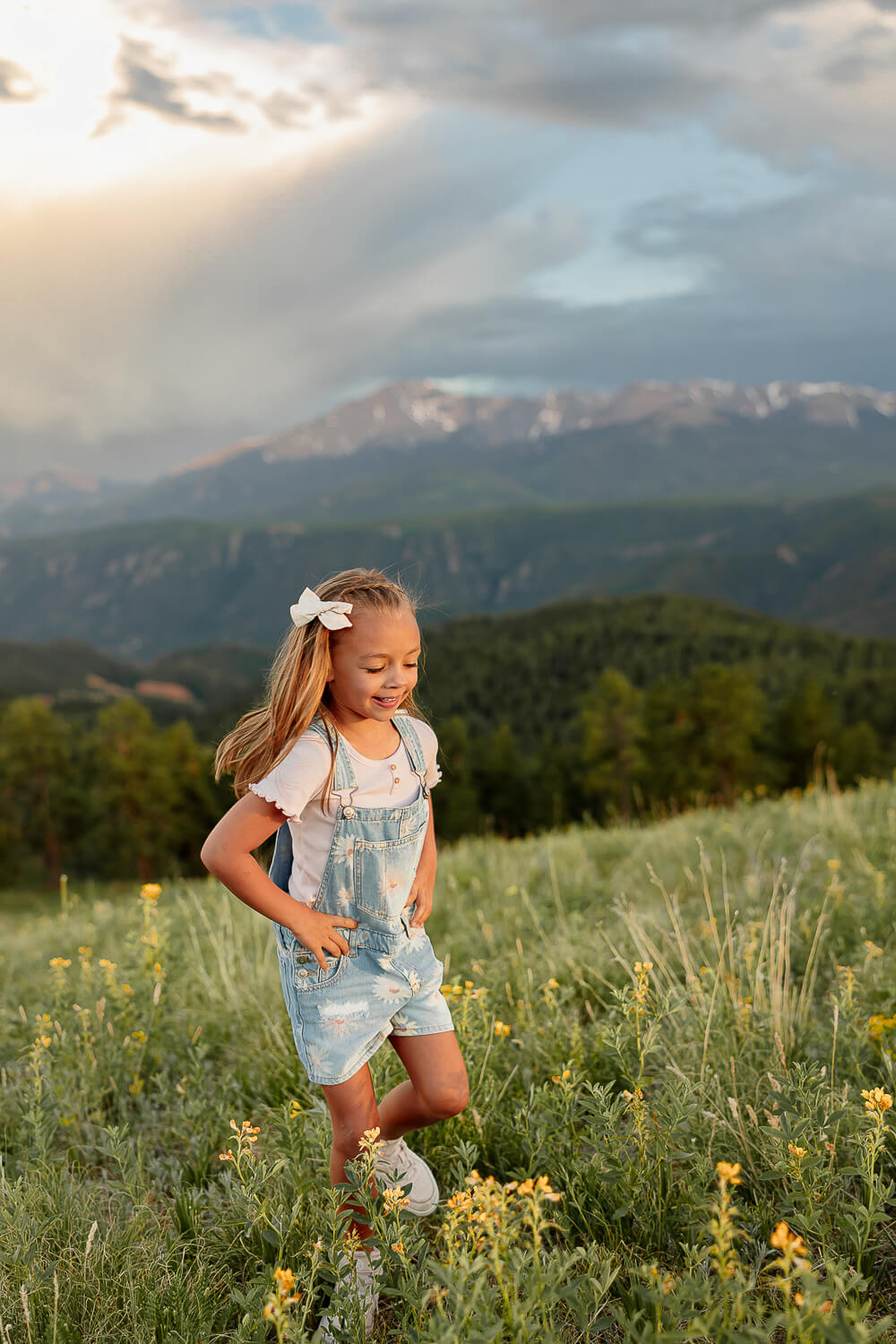 A little girl running through a green grass oasis. Surrounded by mountains and blue skies. A client of Dr. Ryan at Radix Chirorpactic.