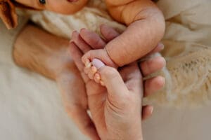 A detail photo of family with newborn baby, all holding hands. Clients at a prenatal chiropractors office in Colorado Springs.